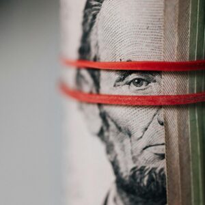 Closeup of rolled United States five dollar bills tightened with red rubber band